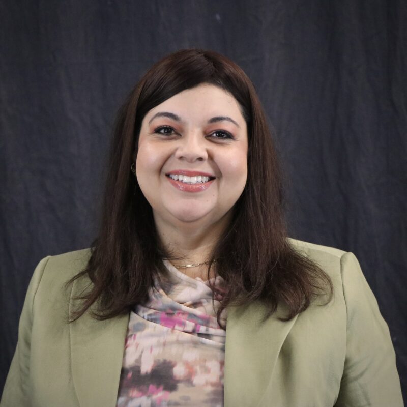 Image of a woman with dark hair wearing a green blazer